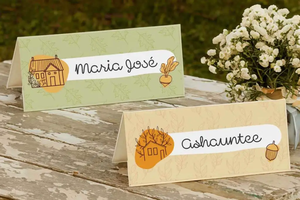 Mockup of printable place cards for thanksgiving on an outdoor wooden table with a vase of white flowers