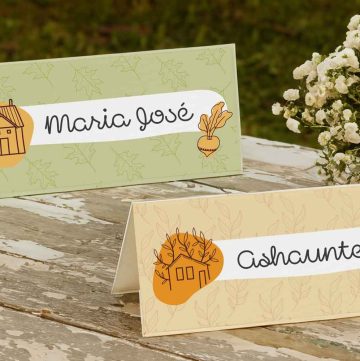 Mockup of printable place cards for thanksgiving on an outdoor wooden table with a vase of white flowers